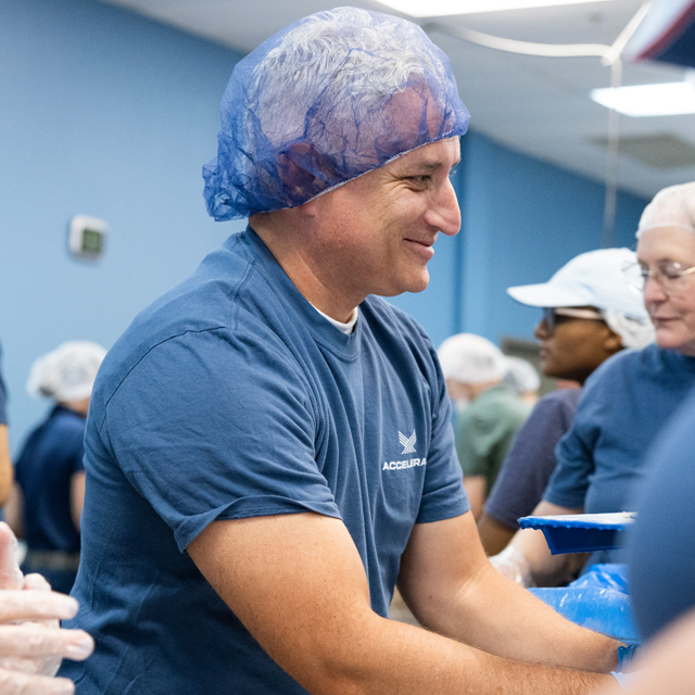 An Accelerate employee smiling as he volunteers at a food bank