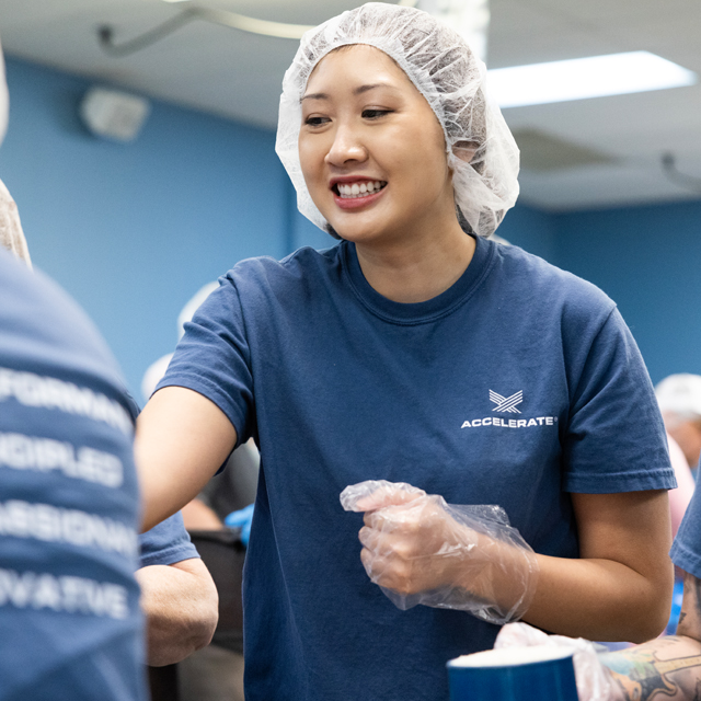 An Accelerate employee smiling as she volunteers at a food bank