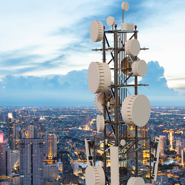 A large cell tower resting on top of a building overlooking a city