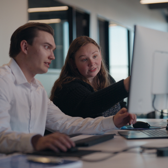 2 employees working together at a computer.